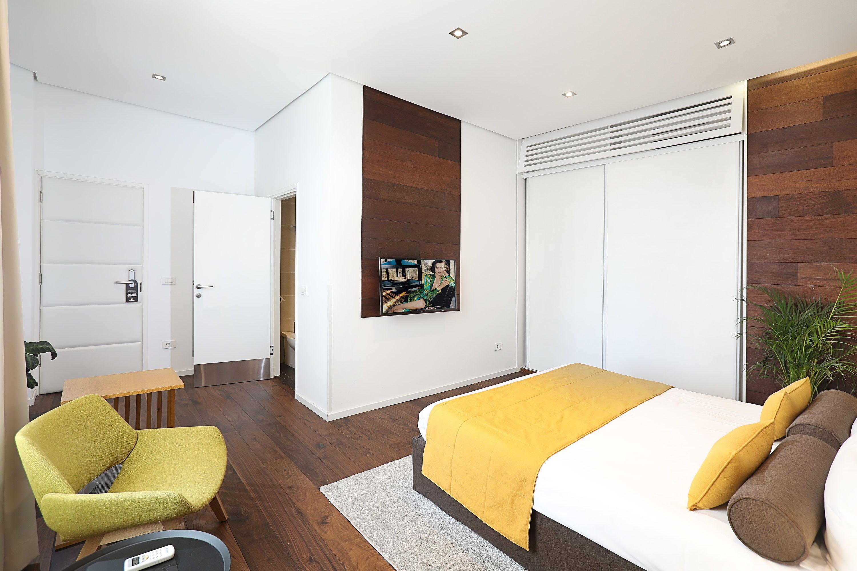 Ein modernes Schlafzimmer mit einem Bett, einem Sessel, einem kleinen Tisch und einem Wandbild.
