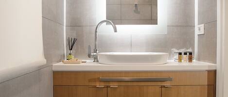 Un baño moderno con un espejo grande, un lavamanos y armarios de madera.