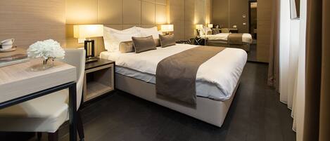 A modern hotel room with a large bed, bedside tables, a desk, and a mirror.