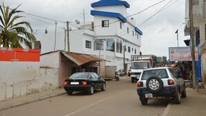 Une rue bordée d’immeubles, une voiture noire et un camion blanc.