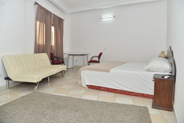 Una habitación de hotel con una cama, un sofá, una mesita y una silla.