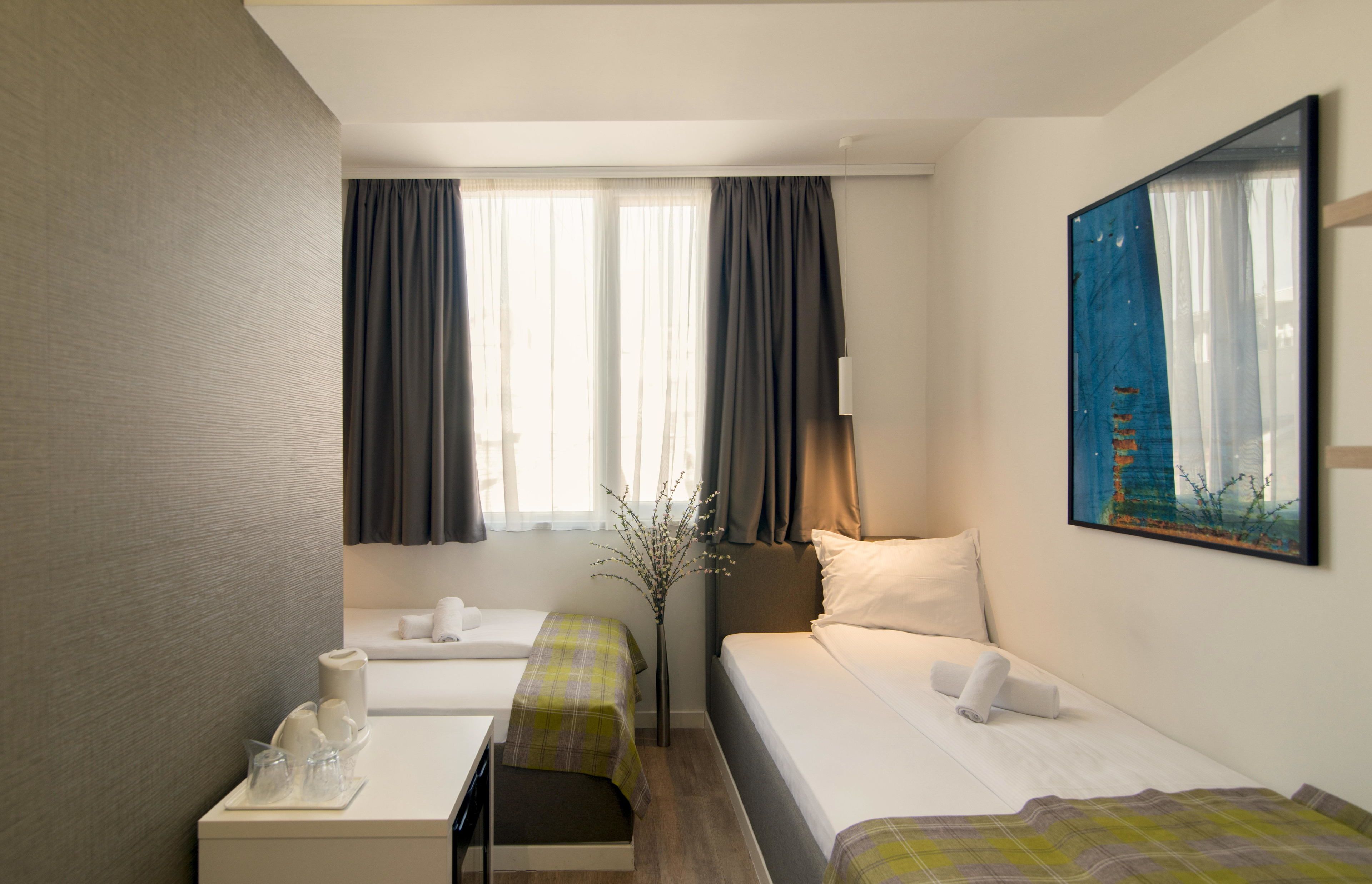 Una habitación de hotel con dos camas, un escritorio y un cuadro en la pared.
