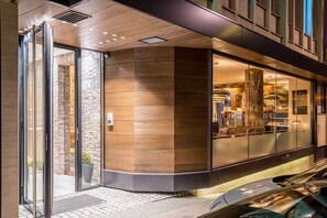 A modern building with a glass entrance, a brick wall, and a wooden panel design.