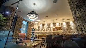 A modern bistro interior with a stone wall, a large chandelier, and a seating area with tables and chairs. - Hotel Belgrade Inn (Belgrade)
