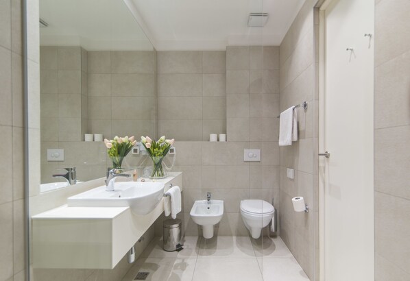 A modern bathroom with a sink, bidet, and toilet.