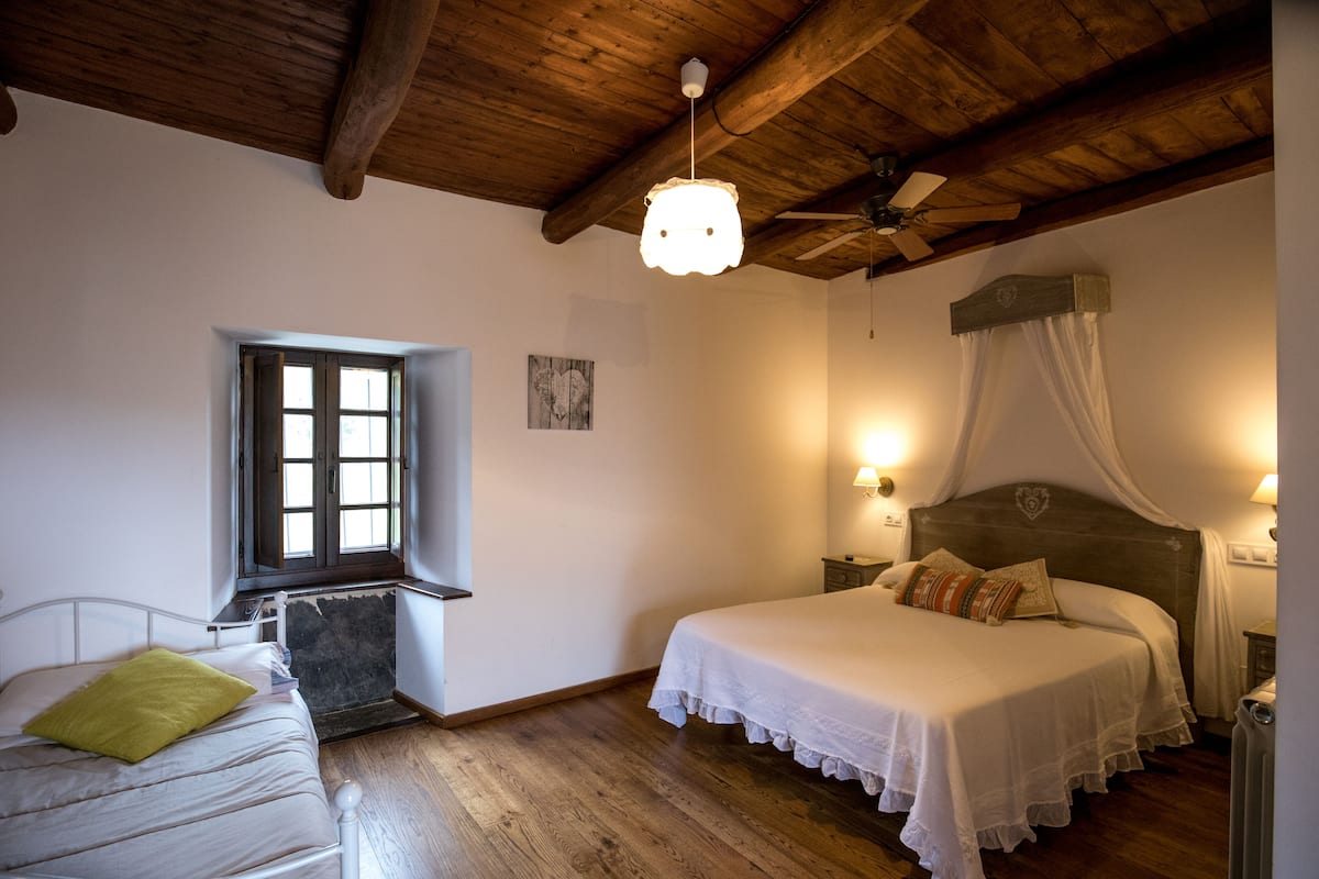 Un dormitori amb llit, finestra i ventilador de sostre.