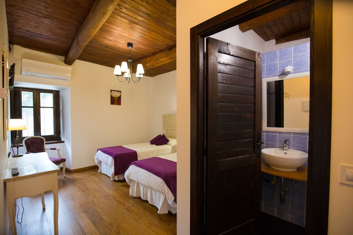 Habitació amb dos llits, una taula, una cadira i una finestra.