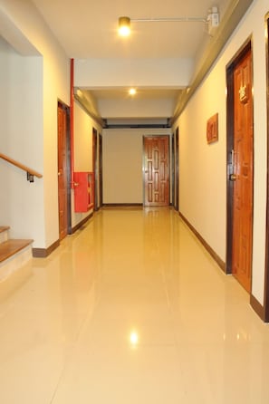 A hallway with a polished floor, wooden doors, and a staircase on the left.
