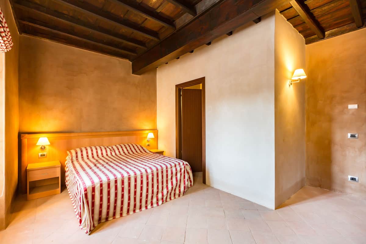 Un dormitorio con cama, lámparas de noche y techo de madera.