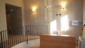 Un área de recepción con un mostrador de madera, una barandilla de metal negro y un termostato fijado a la pared.