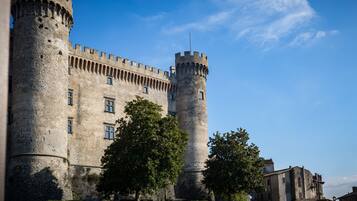 Un castello storico in pietra, con due torri imponenti e un edificio centrale caratterizzato da finestre ad arco.