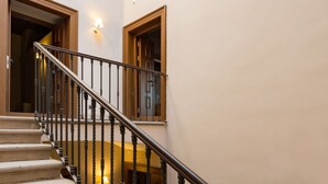 Una escalera con barandal de madera y una lámpara en la pared.