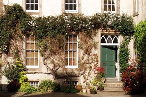 A building with a green door, white-framed windows, and ivy-covered walls. - Edinburgh Landmarks Apartments (Edinburgh)