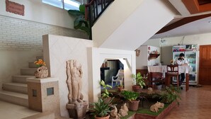 A staircase with a decorative sculpture, potted plants, and a seating area with a table and chairs. - Casa Holiday Hotel (Phitsanulok)