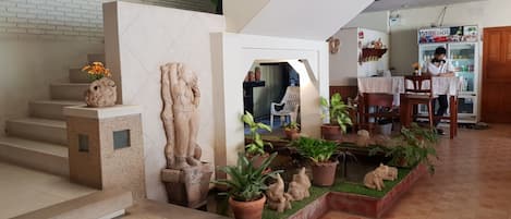 A staircase with a decorative sculpture, potted plants, and a seating area with a table and chairs.