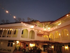 A building with multiple arches and a covered patio area, string lights, and a balcony. - Casa Holiday Hotel (Phitsanulok)