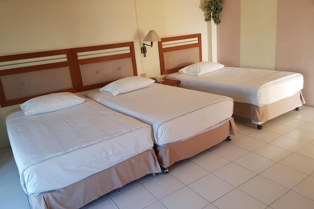 Une chambre d’hôtel avec deux lits, une table de chevet, une lampe et une petite plante.