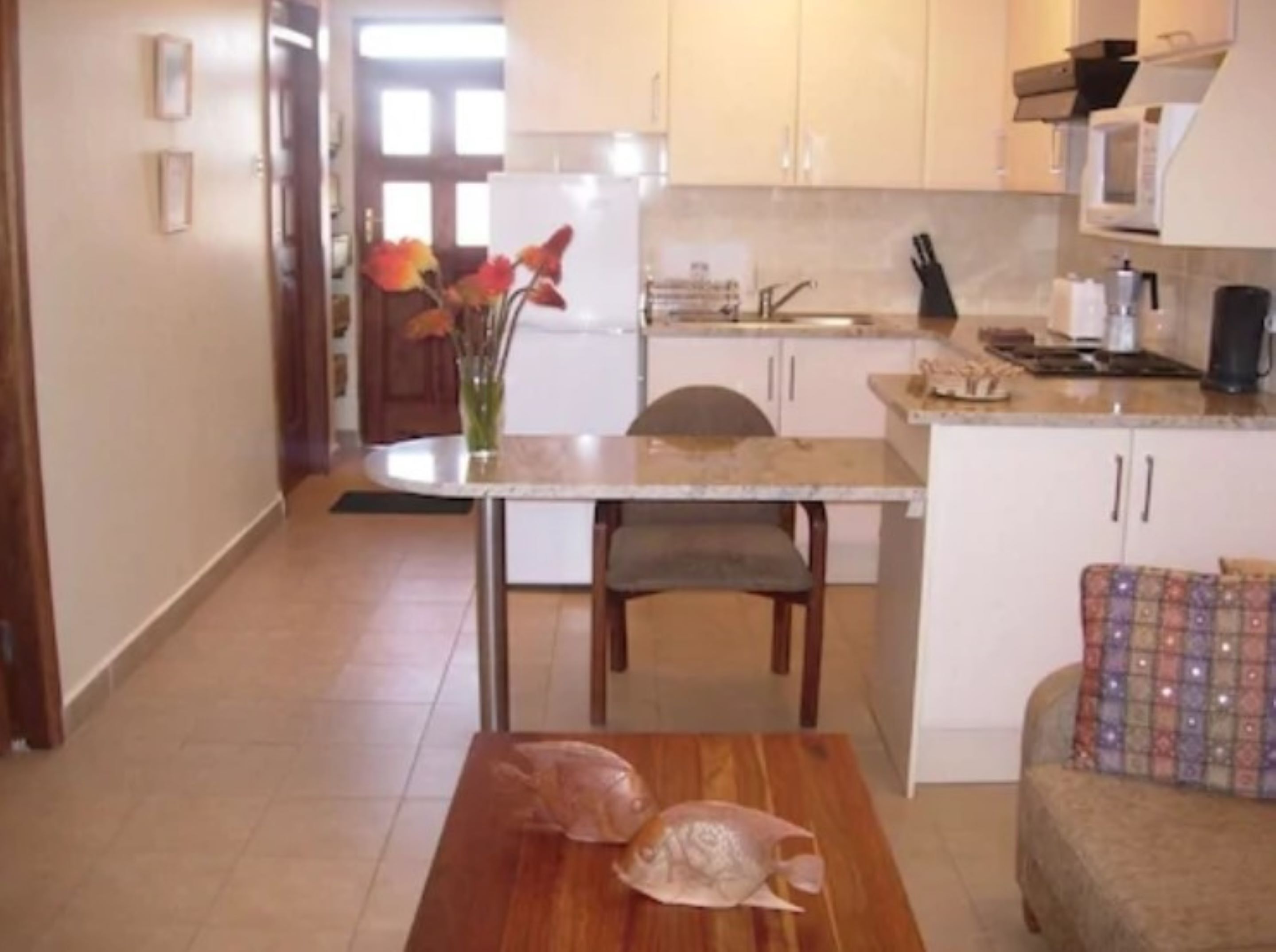 A kitchen with white cabinets, a dining table with chairs, and a fish on the table.