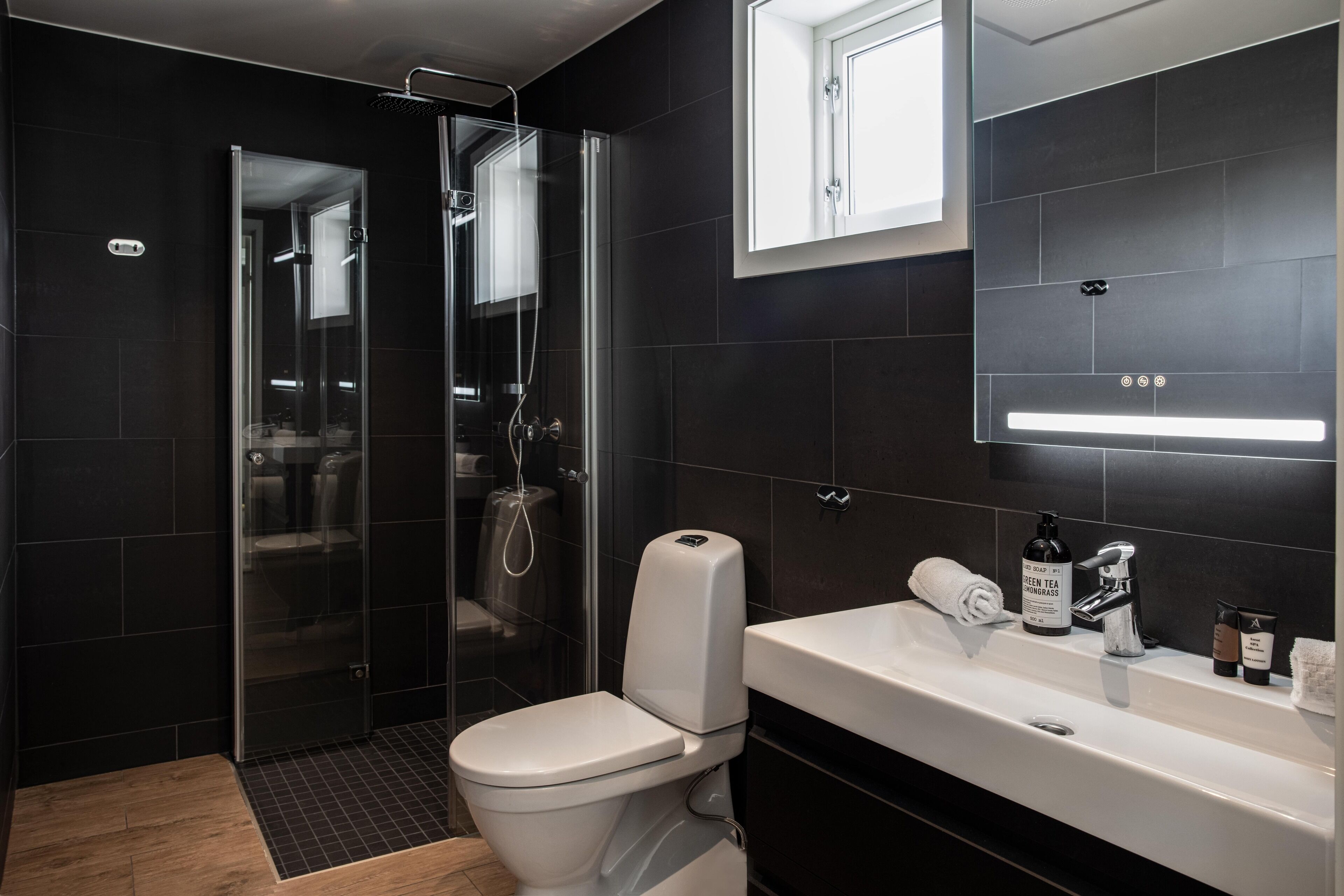 Ein modernes Badezimmer mit einer Duschkabine, einer weißen Toilette und einem Waschbecken mit Spiegel.