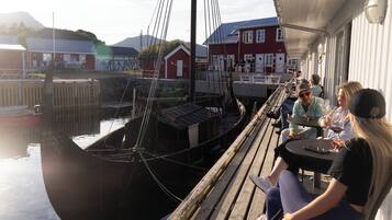 Eine Holzstege mit einem Boot, das in einer Marina festgemacht ist, umgeben von Gebäuden und einer Bergkulisse.