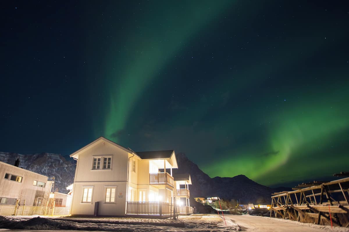 Un bâtiment à deux étages doté d’un balcon, situé dans une région enneigée, avec des montagnes en arrière-plan.