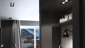 Une cuisine moderne dotée d’un évier encastré, de meubles de rangement aux couleurs sombres et offrant une vue sur les montagnes grâce à une grande fenêtre.