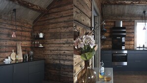 Une cuisine rustique aux murs en bois, dotée d’appareils électroménagers modernes et agrémentée d’un vase rempli de fleurs posé sur le comptoir.