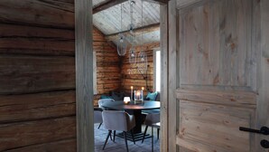 Un intérieur en bois comprenant un coin repas avec une table ronde, des chaises et des luminaires suspendus.