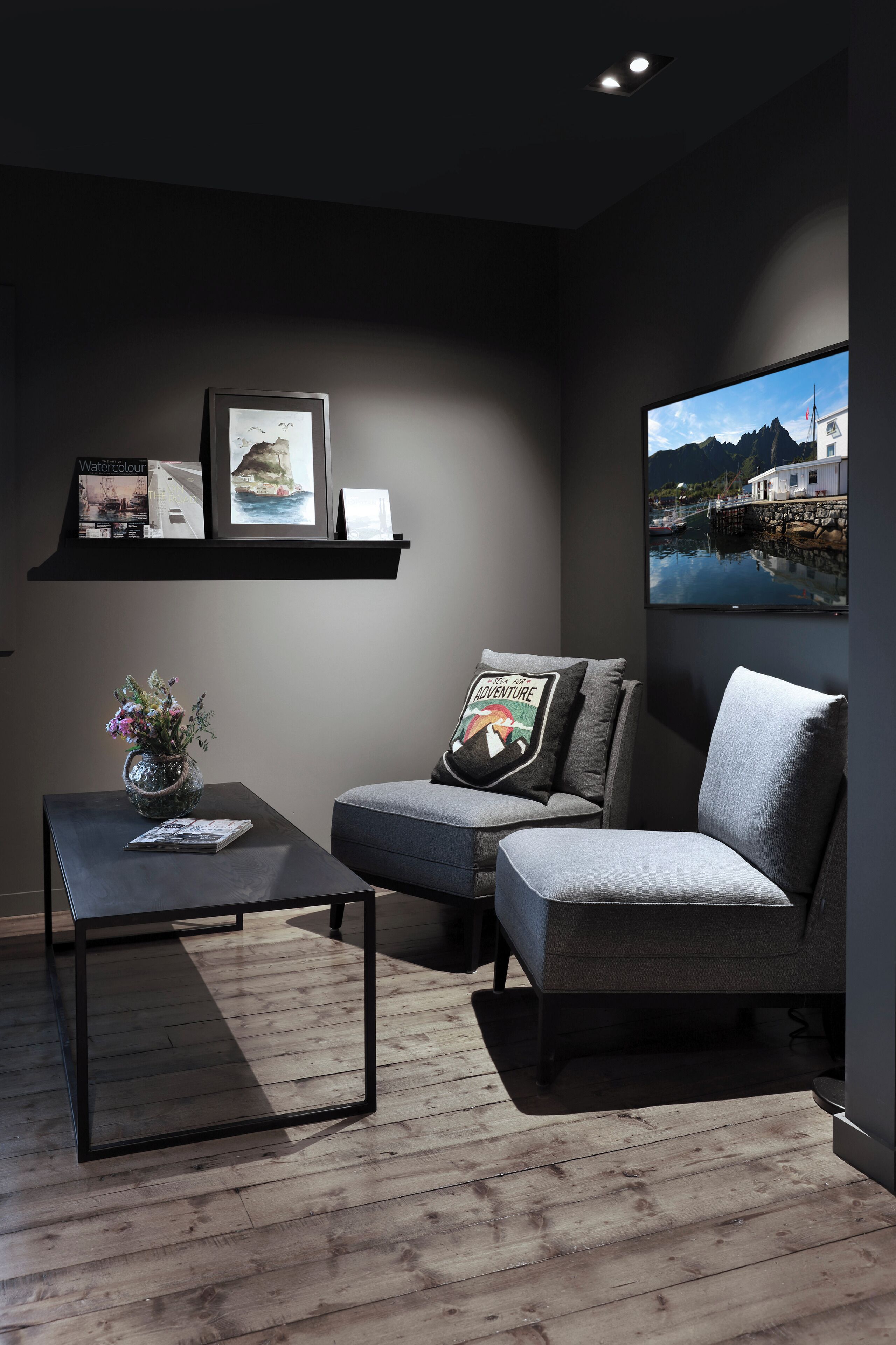 Una sala de estar moderna con un sofá gris, una mesa de centro y un televisor montado en la pared.