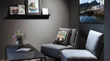 Una sala de estar moderna con un sofá gris, una mesa de centro y un televisor montado en la pared.
