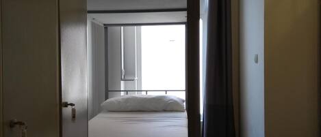 A bunk bed room with a wardrobe, a window, and a curtain.