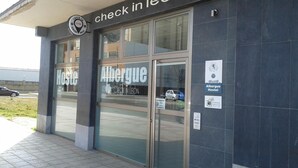 A hostel with a glass entrance, a sign for 'check in león', and a 'Albergue Hostel' sign.