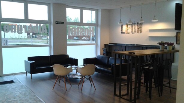 A modern interior with a black leather sofa, two white chairs, a wooden table, and hanging pendant lights.