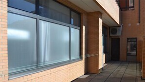 A building exterior with large windows, a brick facade, and a tiled walkway.