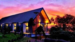 A modern house with a sloped roof, multiple windows, and a well-lit entrance. - Kirirath Resort (Pak Chong)