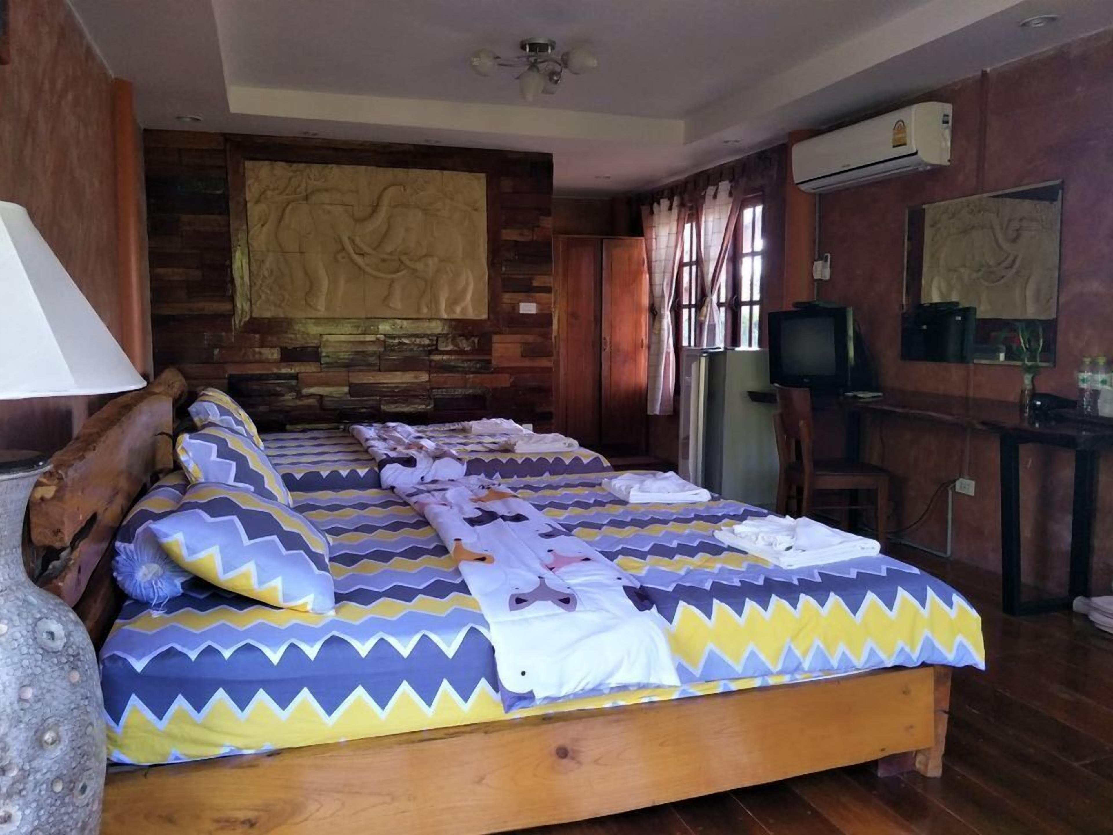 Una habitación con una cama grande, televisión y aire acondicionado.