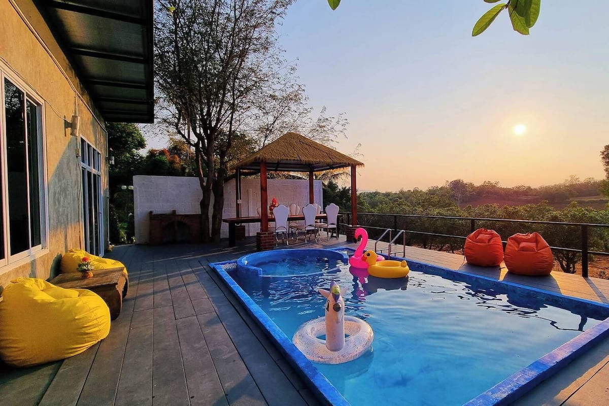 A swimming pool with a hot tub, surrounded by outdoor seating and a gazebo.