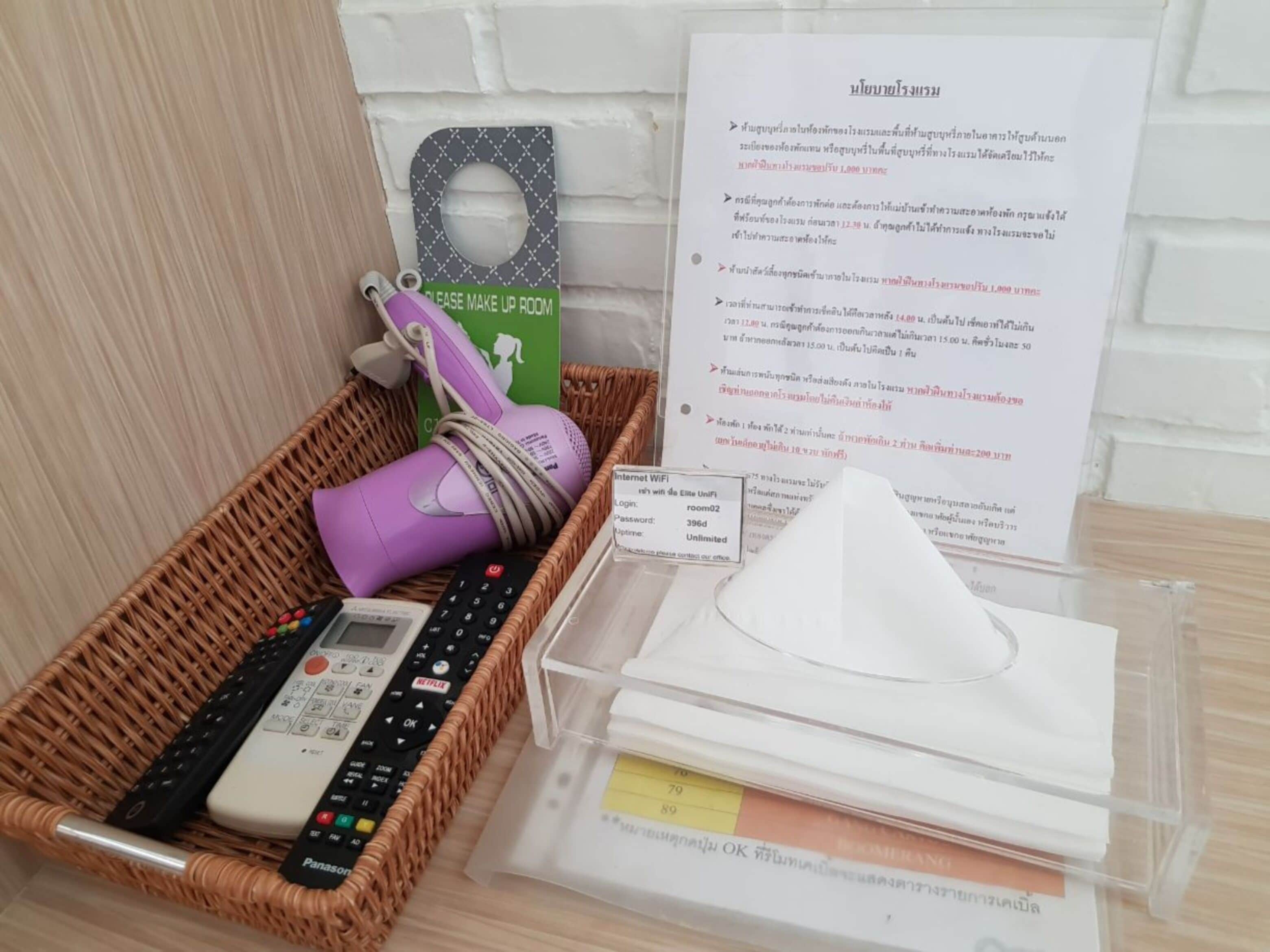 A room with a wicker basket containing a remote control, a purple device, and a sign indicating a 'Please Make Up Room' area.