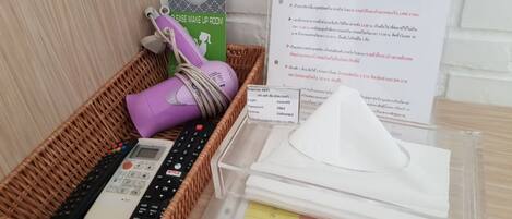 A room with a wicker basket containing a remote control, a purple device, and a sign indicating a 'Please Make Up Room' area.