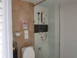 Un baño con inodoro, ducha y letrero de prohibido fumar.