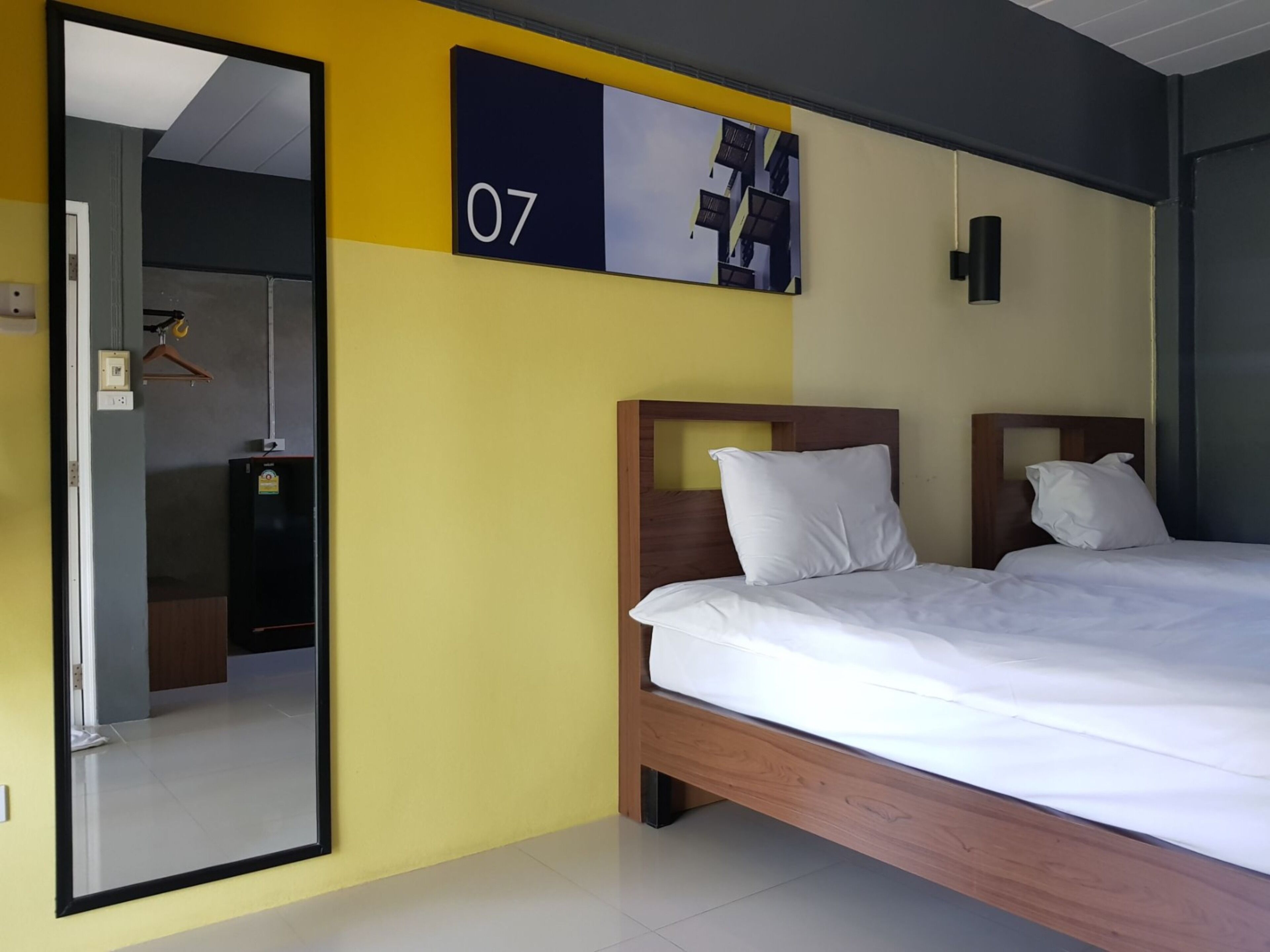 A hotel room with a large bed, a mirror, and a wall-mounted number sign.