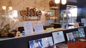 A reception desk with 'elite Phitsanulok' signage, a mirror, and informational brochures. - Elite Residence Phitsanulok (Phitsanulok)