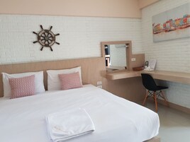 Habitación de hotel con cama, escritorio, silla, decoración de timón de barco y un cuadro en la pared.