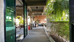 A corridor with a glass door leading to a dining area, a brick wall, and a planter with greenery. - Elite Residence Phitsanulok (Phitsanulok)