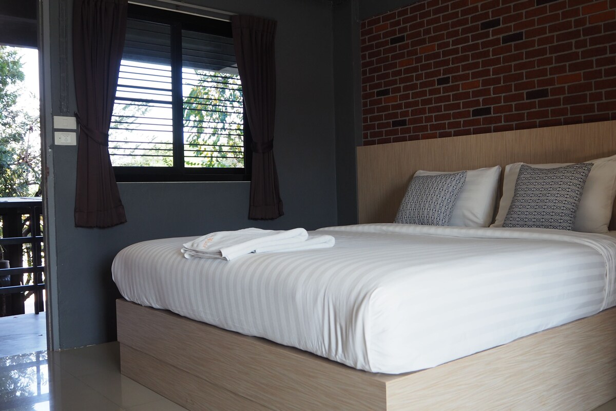 Ein modernes Hotelzimmer mit einem großen Bett, einem Holzkopfende und einer Ziegelwand.