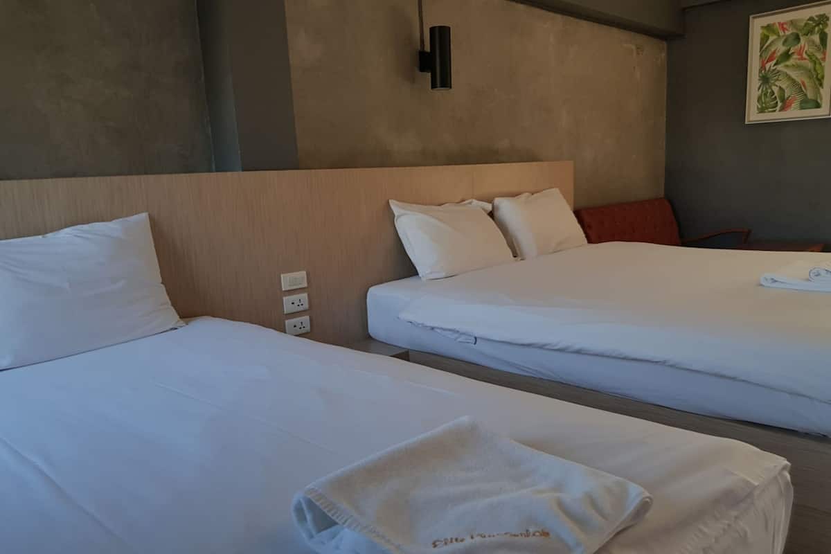 A hotel room with two beds, each with white linens and pillows. There is a folded towel on the bed in the foreground.
