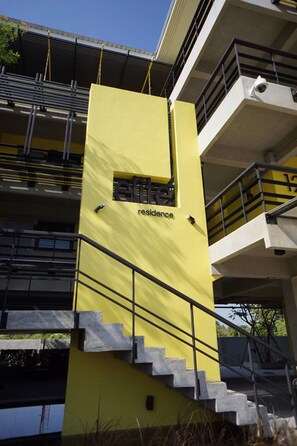A yellow building with the word "residence" on it, a staircase, and a balcony. - Elite Residence Phitsanulok (Phitsanulok)