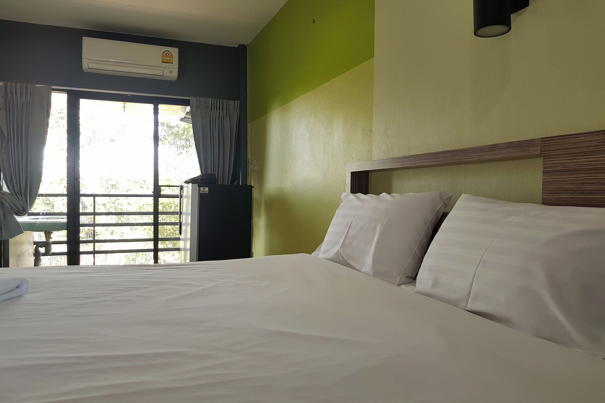 Ein Hotelzimmer mit Bett, Vorhängen, einer Klimaanlage und Blick durch ein Fenster.