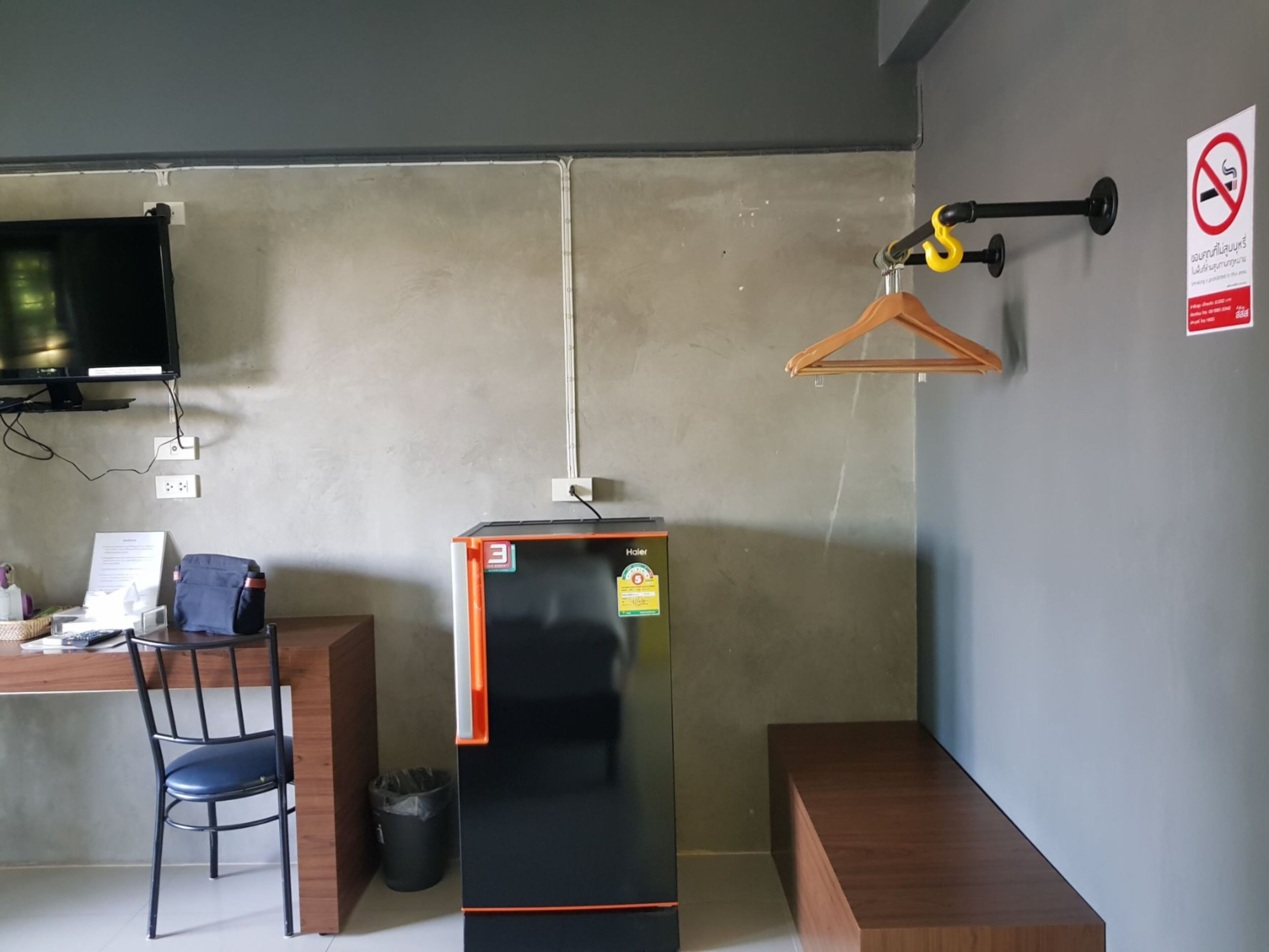Una habitación de hotel compacta con escritorio, silla y un refrigerador negro.