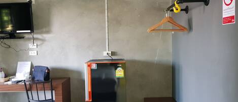 Una habitación de hotel compacta con escritorio, silla y un refrigerador negro.